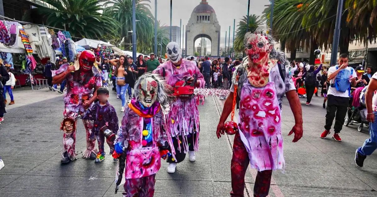 Tres adultos y dos niños con batas y máscaras de látex llenas de sangre caminando por avenida Revolución.jpg
