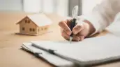 Persona redacta su testamento junto a maqueta de casa.