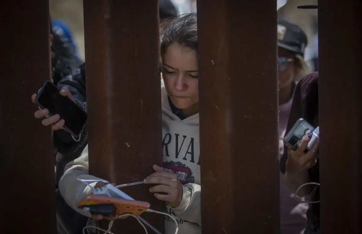 Migrantes en el muro fronterizo entre Estados Unidos y México.