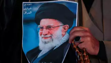 Un hombre musulmán chiíta sostiene un cartel del difunto líder supremo iraní Ayatolá Ali Khamenei, asesinado en un ataque estadounidense-israelí contra Teherán, y un conjunto de cuentas de oración durante un mitin en la Plaza Tahrir, en Bagdad, el 6 de marzo de 2026.