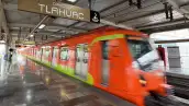 Un tren de color naranja con vivos verdes con un letreo que dice Tláhuac, una persona en el anden.jpg