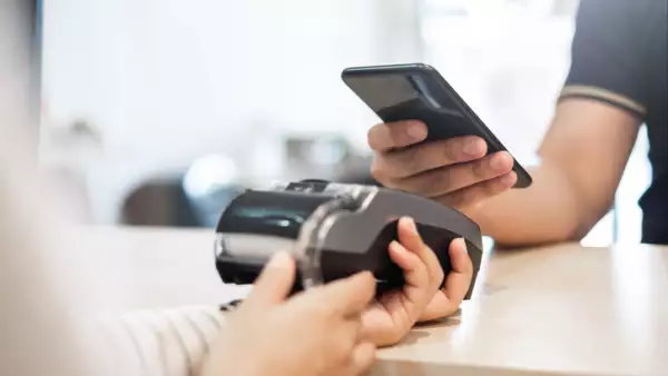 Customer using phone for payment to owner at cafe restaurant, cashless technology and credit card payment concept