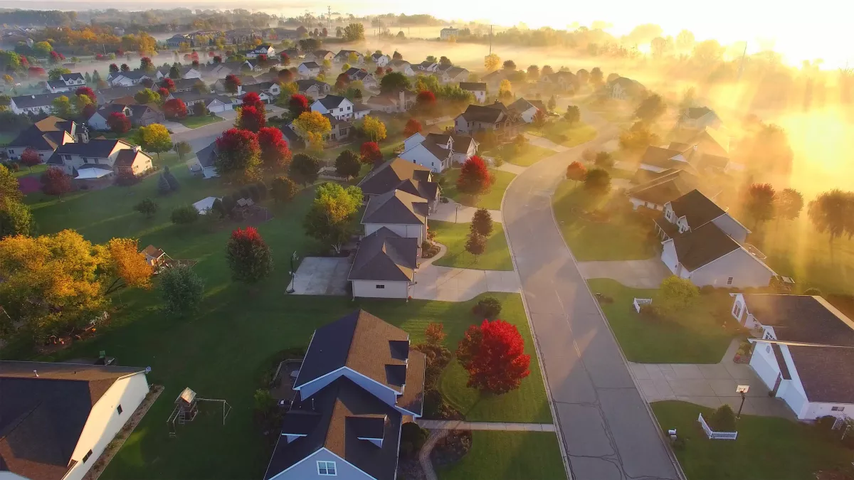 Magical foggy sunrise over sleepy neighborhood with shadows and sunbeams