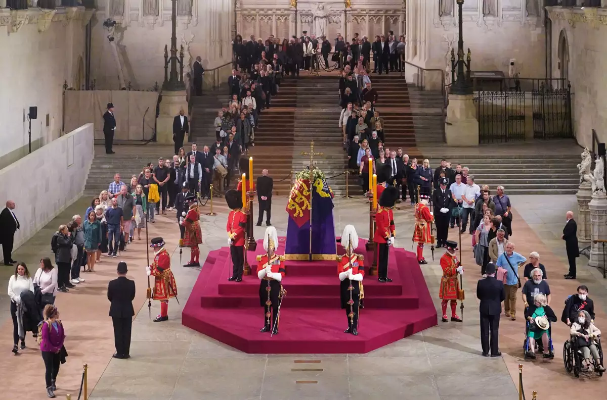 Los miembros del público hacen cola, frente a la Torre Victoria del Palacio de Westminster, mientras esperan en fila para presentar sus respetos a la difunta Reina Isabel II, en Londres el 15 de septiembre de 2022.