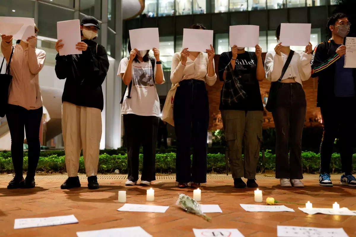 Gente sostiene hojas de papel en una protestas por las restricciones en China continental durante la conmemoración de las víctimas de un incendio en Urumqi, en la Universidad de Hong Kong, en Hong Kong, China. 