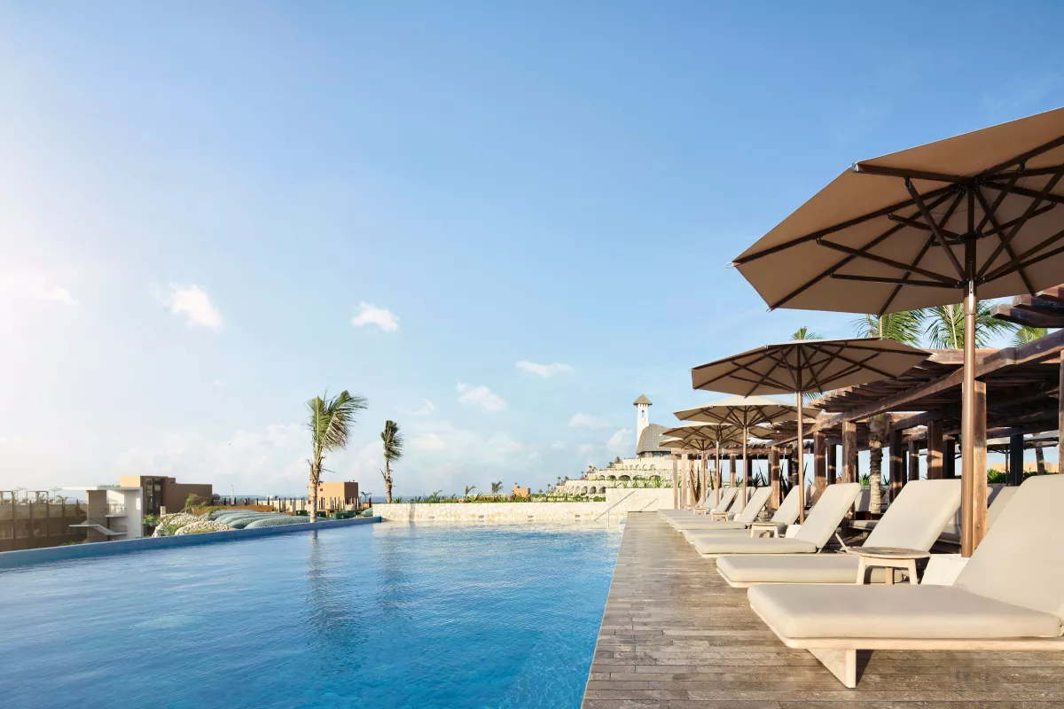 Rooftop del Hotel Xcaret Arte con sombrillas y tumbonas frente a la alberca