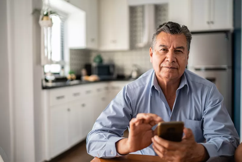 Portrait of mature man using mobile phone at home