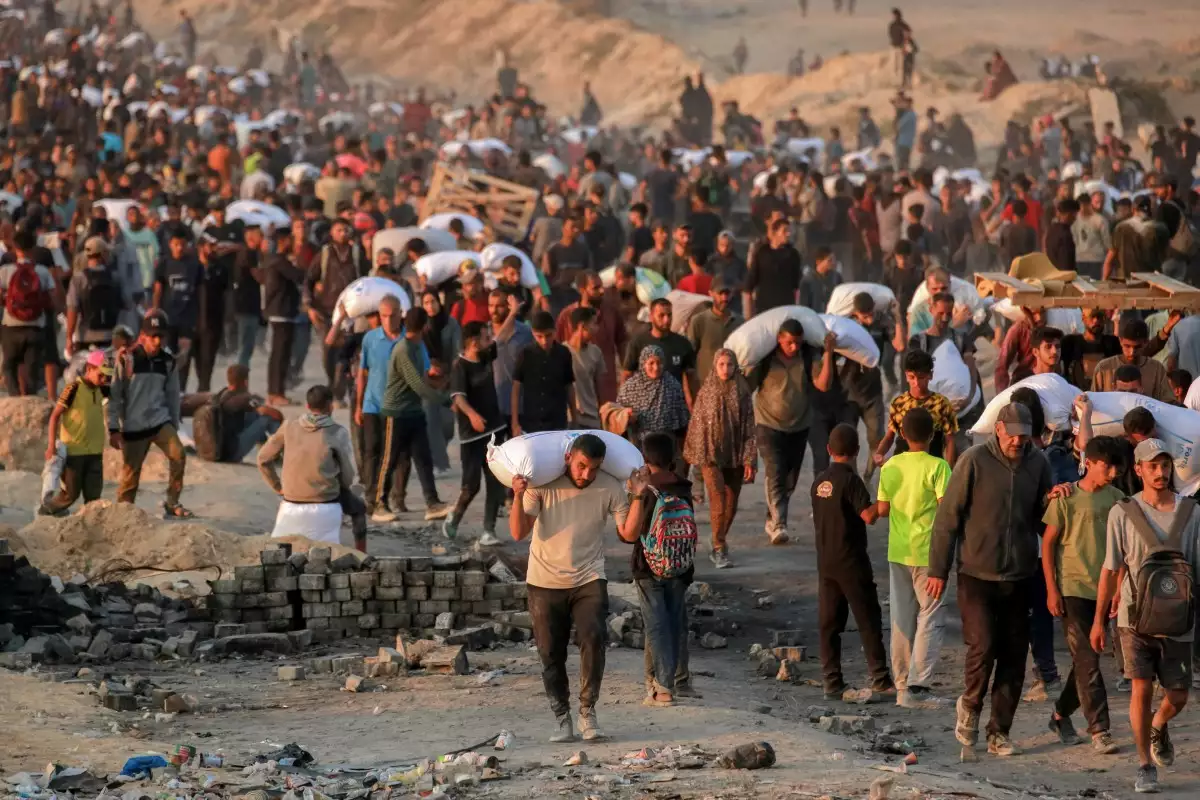 Las personas que llevaban sacos de harina caminan por la calle al-Rashid en el oeste de Jabalia el 17 de junio de 2025, después de que camiones de ayuda humanitaria supuestamente entraran en el norte de la Franja de Gaza a través del cruce fronterizo de Zikim controlado por Israel, en medio de la guerra en curso entre Israel y Hamas.
