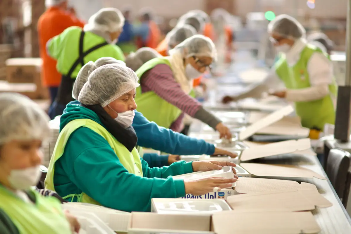 Trabajadoras arman cajas en una línea de producción. 