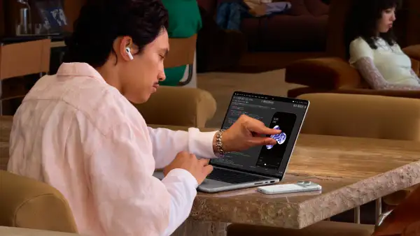Usuario tocando la pantalla de la MacBook Pro PROLED XDR, la cual ahora tiene funciones táctiles.