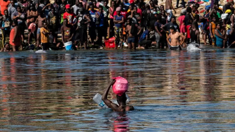 Asylum-seeking migrants wait to be processed under the International Bridge in Del Rio, Texas