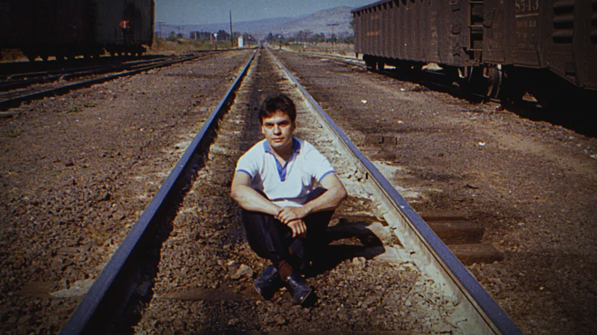 Fotografia de archivo de un sonriente Juan Gabriel cuando era joven. El cantante mexicano está sentado en las vias del tren.