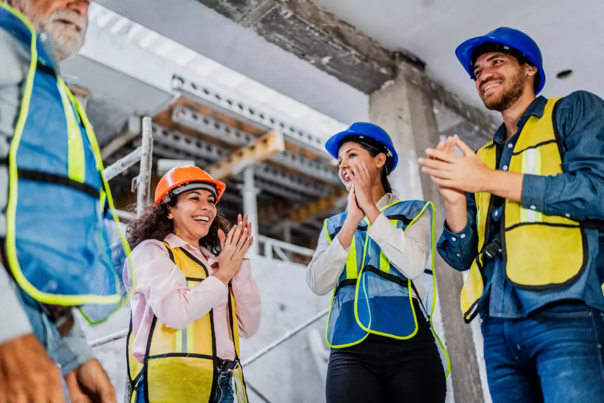 Coworkers celebrating and applauding on construction site