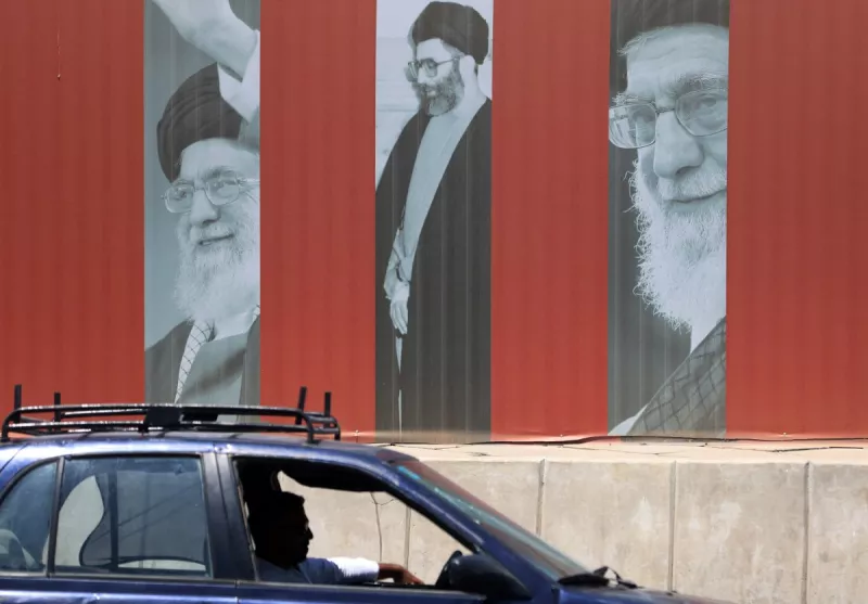 Un coche pasa por delante de una valla publicitaria que muestra fotos del difunto líder supremo de Irán, el ayatolá Ali Khamenei, a lo largo de una calle de Bagdad el 2 de julio de 2026, antes de su funeral en Teherán.