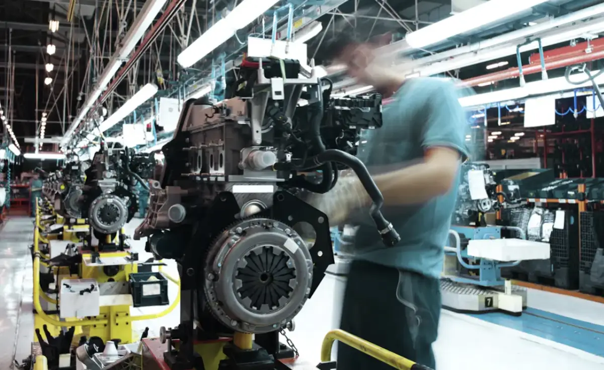 Un trabajador participa en la colocación de tornillos para la fabricación de un motor en una planta de autopartes en México. 