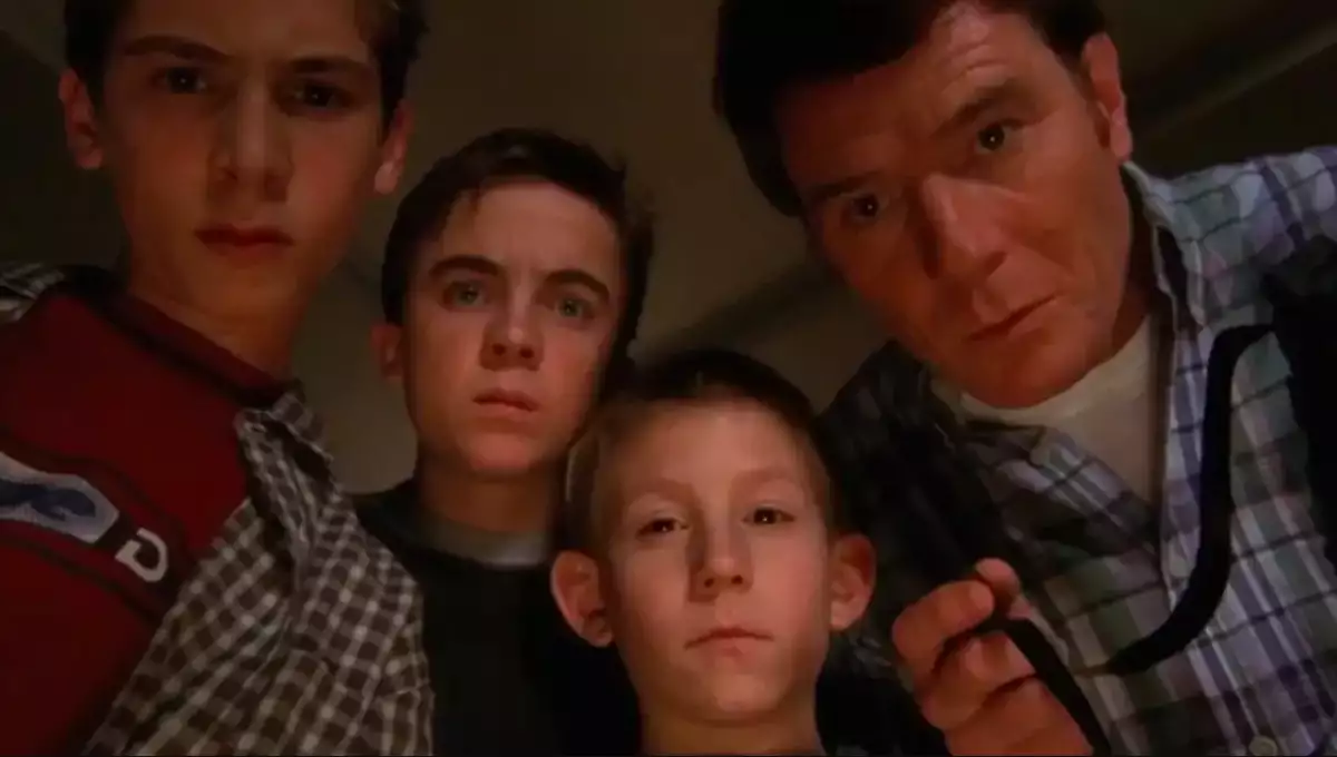 Foto de una escena de la serie 'Malcolm, el de en medio', con los personajes de Reese, Malcolm, Dewey y Hal viendo con gesto serio hacia abajo.