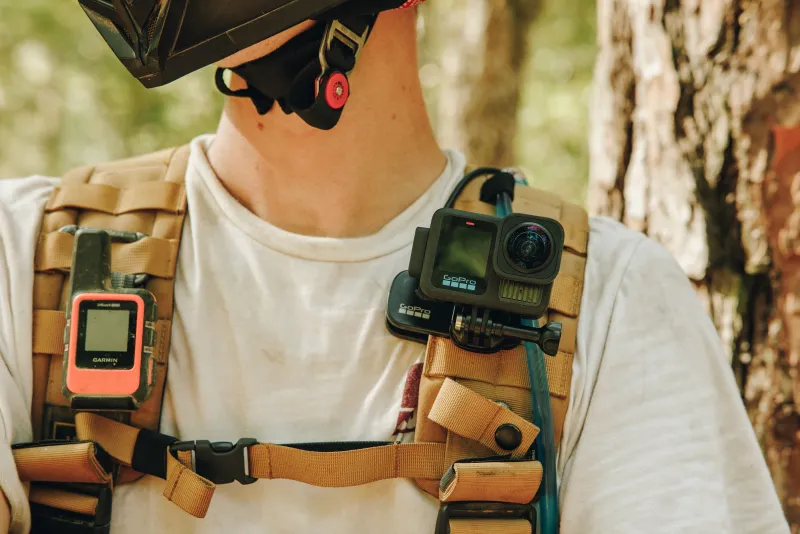 Primer plano de una cámara GoPro sobre el hombro de un usuarios, quien parece ser un ciclista de montaña.