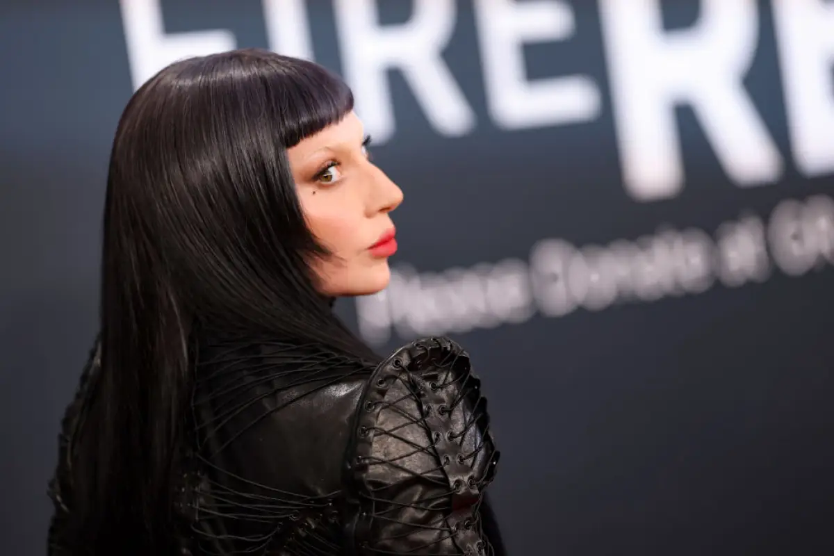 Foto de perfil de Lady Gaga con look gótico: cabello negro, fleco corto, labios rojos y ropa de cuero negra.