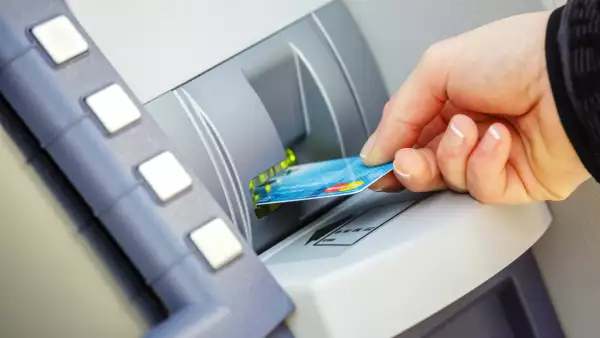 Young woman inserting her bank card in a distributor of banknotes