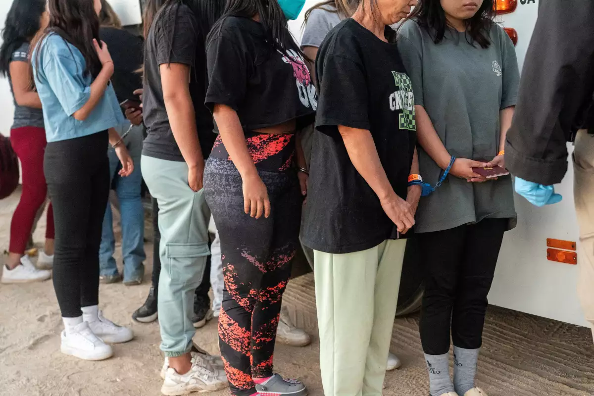 Los migrantes son esposados como pareja antes de subir a un autobús para ser transportados después de cruzar la frontera a los EE. UU. desde México en Jacumba Hot Springs, California, EE. UU., el 11 de noviembre de 2023.