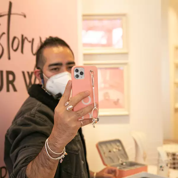 Persona sosteniendo en alto un celular con funda y charm holder de Pandora