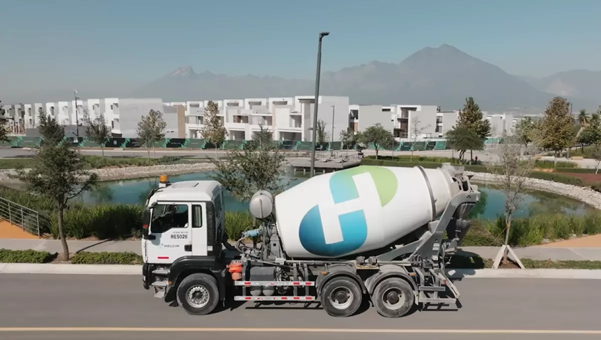 Camión revolvedora de concreto de Holcim y al fondo se observan viviendas color blanco.