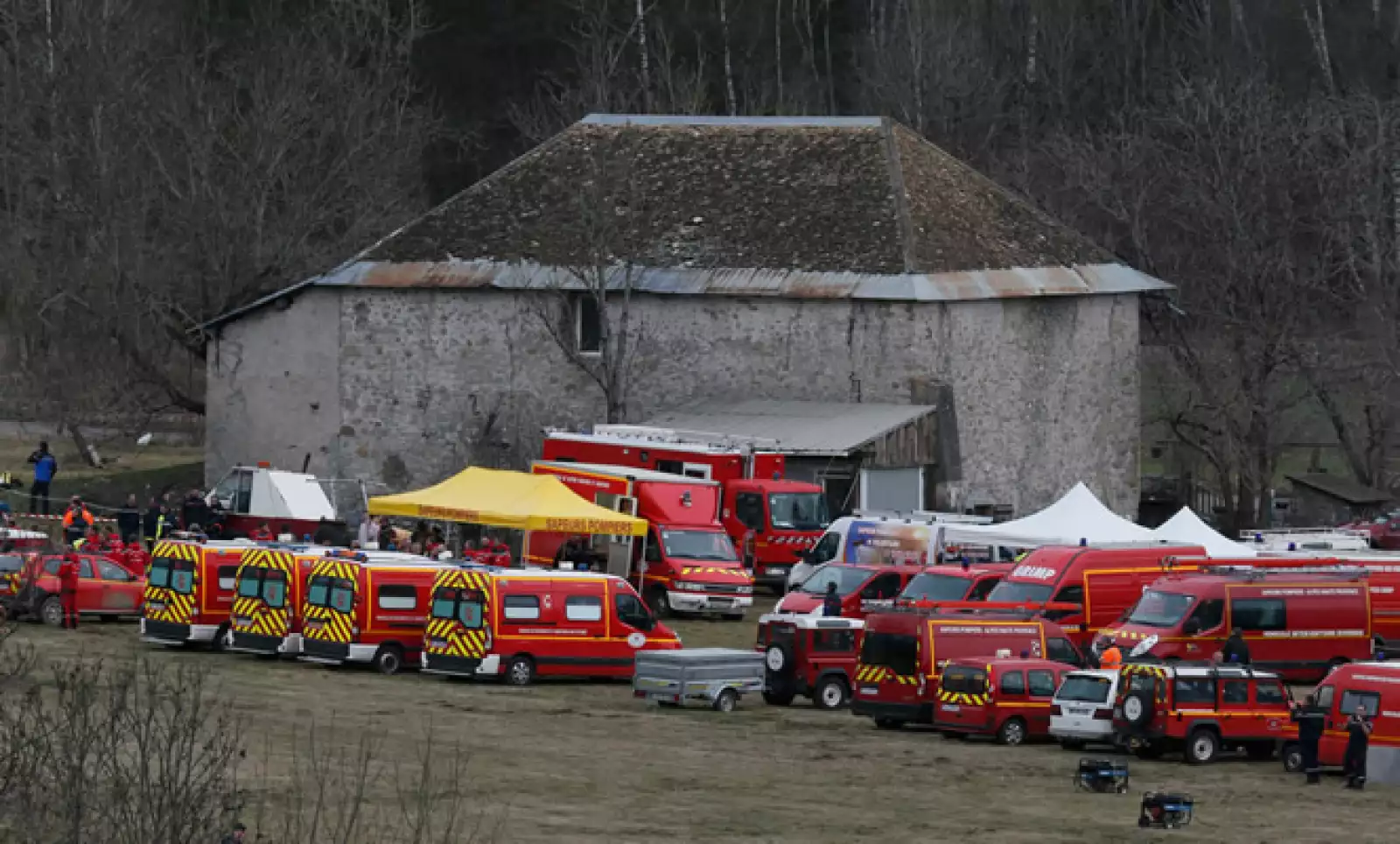 Unidades de rescate del cuerpo de bomberos franceses se reúnen en un campo cerca a de una granja y se preparan para llegar al lugar del accidente. 