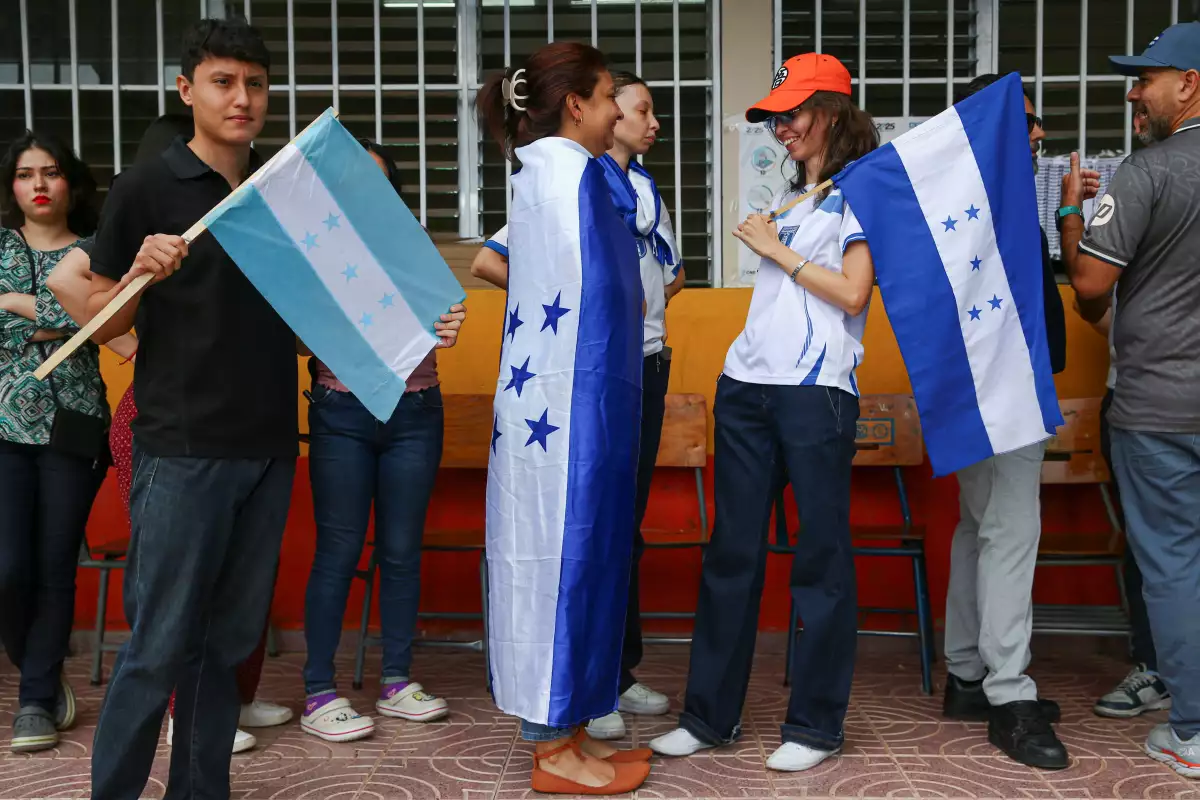 Una mujer con una bandera hondureña hace cola para votar durante las elecciones generales en Tegucigalpa, Honduras, el 30 de noviembre de 2025.
