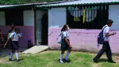 Niñas caminando con uniforme y mochila escolar.