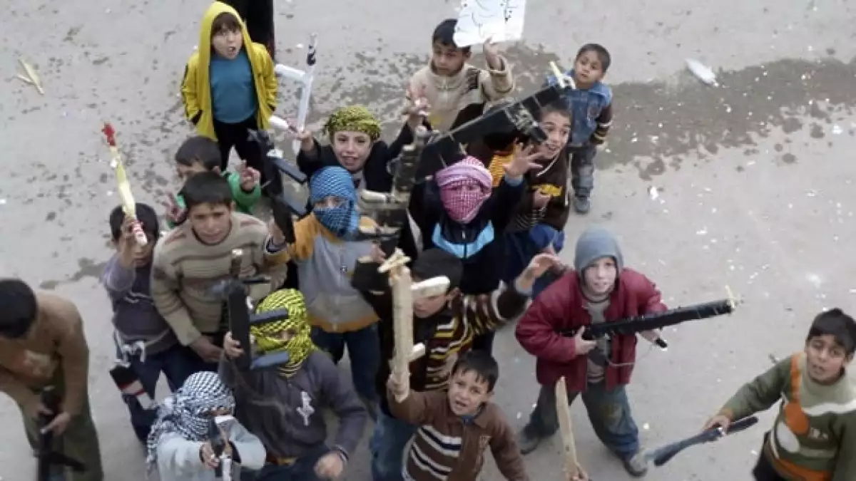 niños sirios sostienen armas de juguete durante una protesta