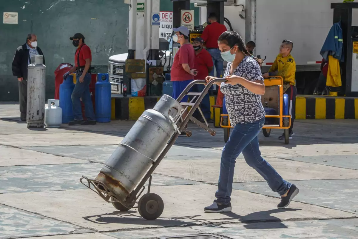 Una mujer lleva su tanque de gas LP, cuyo precio promedio subió un 25% anual 