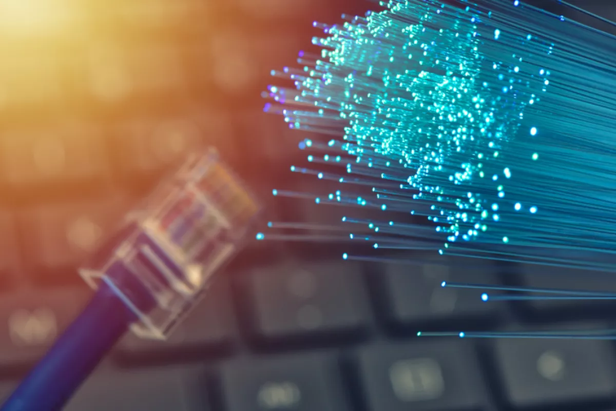 Fiber optics in blue, close up with ethernet and keyboard background, warm lens flare