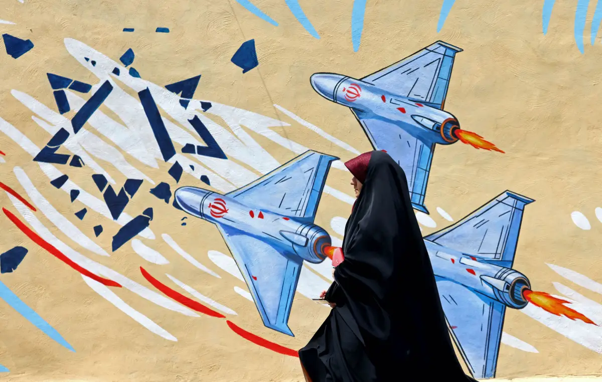 Una mujer pasa junto a un mural anti-EE. UU. y anti-Israel, en Teherán el 8 de abril de 2026. Estados Unidos e Irán acordaron un alto el fuego de dos semanas apenas una hora antes de la fecha límite del 8 de abril del presidente de los Estados Unidos para acabar con el país, lo que provocó el alivio mundial junto con la aprehensión.
