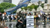 Los manifestantes se protegen detrás de una pancarta que dice "La reforma laboral mata mi libertad" de un cañón de agua disparado por la policía antidisturbios durante una protesta convocada por los sindicalistas contra el debate sobre la reforma laboral que tiene lugar en el Congreso Nacional en Buenos Aires el 11 de febrero de 2026.
