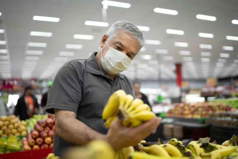 Senior man with disposable medical mask shopping in supermarket