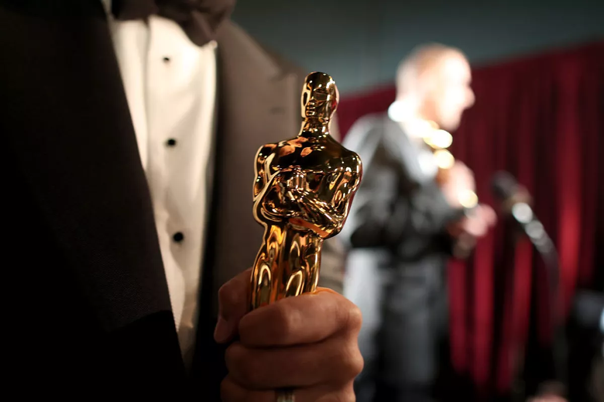 Foto de un close up de una estatuilla del Oscar en manos de un hombre.
