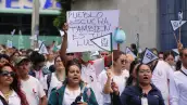 Un grupo de trabajadores sindicalizados del IMSS, vestidos de blanco y verde, marcha por calles de Cuernavaca con cárteles blancos y banderas del IMSS en demanda de aumento salarial, el 8 de octubre de 2026.