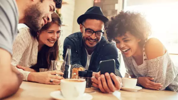 Un grupo de amigos está reunido y comprobando desde un smartphone las novedades de la app de HSBC México, como DIMO y DIAO