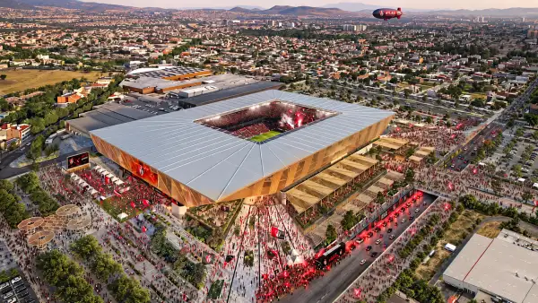 Render aéreo del nuevo estadio del Atlas en Zapopan, con cancha de futbol, tribunas llenas, explanadas exteriores y zonas urbanas alrededor.