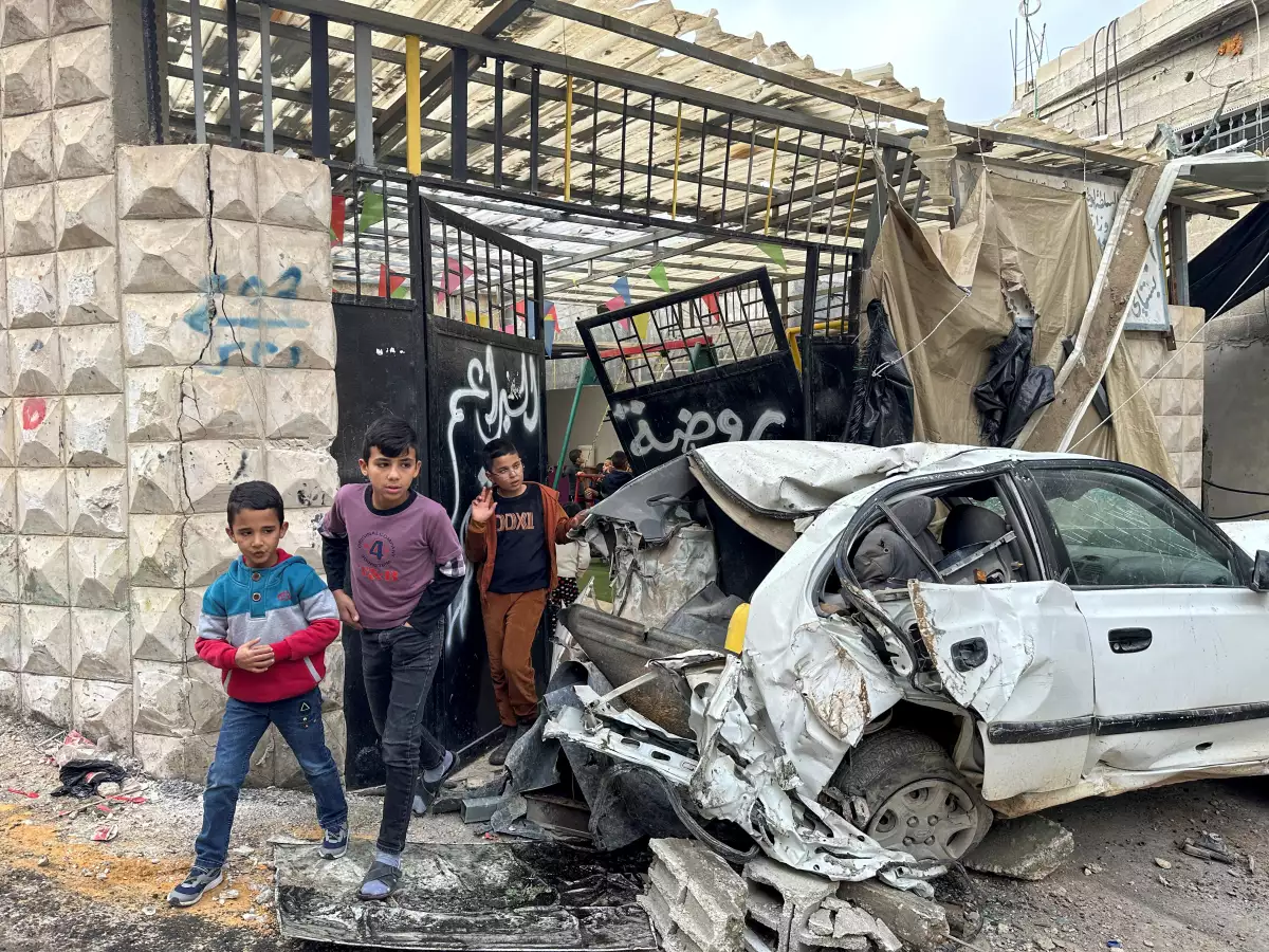 Los niños palestinos caminan cerca de un coche dañado después de una incursión israelí, en Tulkarm, en la Cisjordania ocupada por Israel, el 17 de diciembre de 2023.