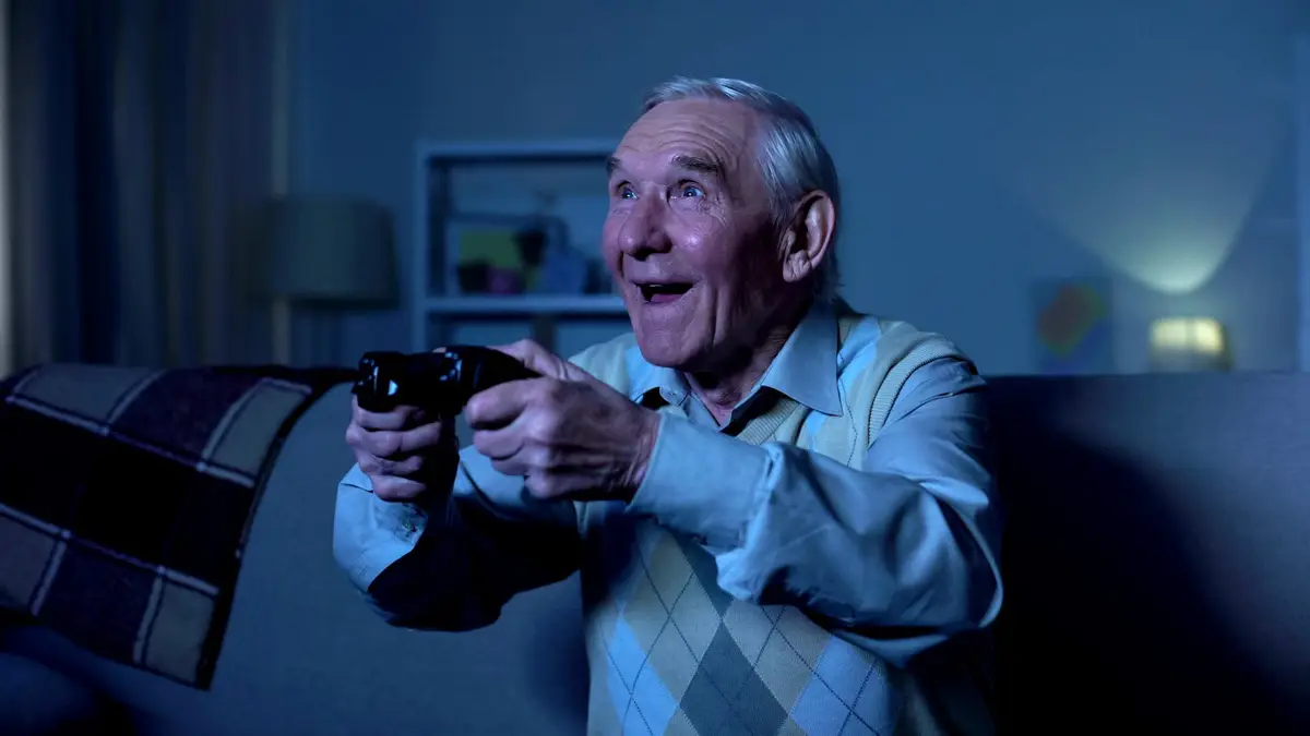 Un abuelo y un joven jugando videojuegos. 