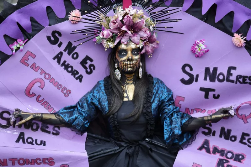 Una mujer desfila con una lectura escrita "Si no ahora, ¿cuándo? Si no es aquí, ¿dónde? Si no eres tú, ¿quién? Si no con amor y rebelión, ¿cómo? Durante una manifestación con motivo del Día Internacional de la Mujer en Madrid el 8 de marzo de 2026