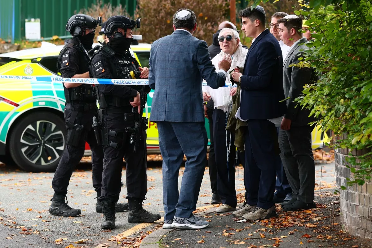 Los policías armados hablan con miembros de la comunidad cerca de la sinagoga de la Congregación Hebrea de Heaton Park en Crumpsall, al norte de Manchester, el 2 de octubre de 2025, después de un incidente en la sinagoga.