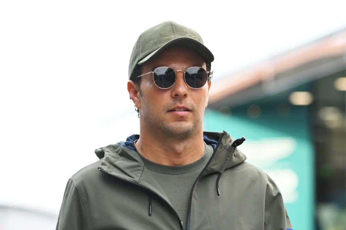 Foto de Checo Pérez con gorra y chamarra verde grisáceo y lentes oscuros