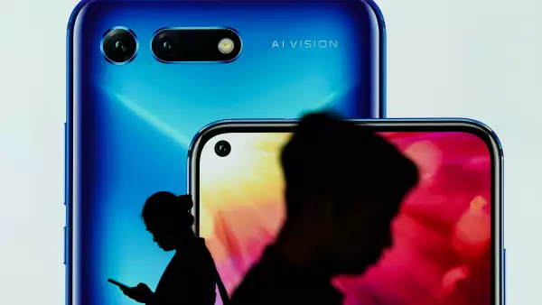 People walk past an advertisement for Huawei's Honor smartphones at an airport in Shenzhen