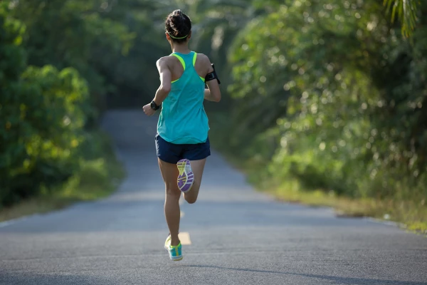 Young fitness woman running on tropical forest trail