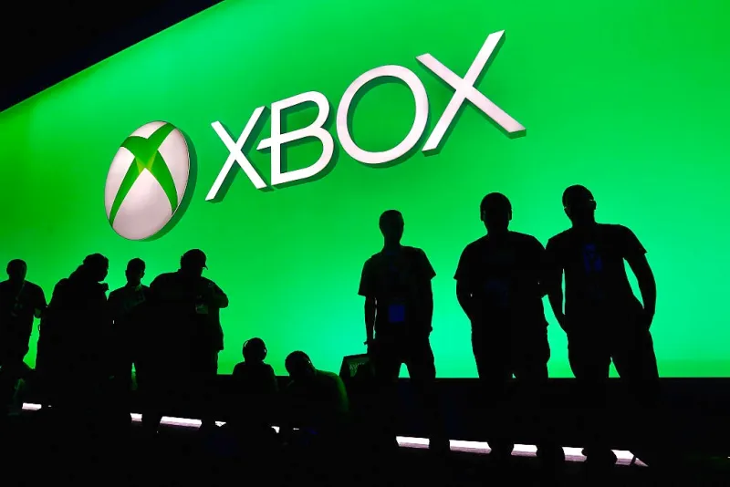 Asistentes a panel de Xbox posan frente al logo de la marca.