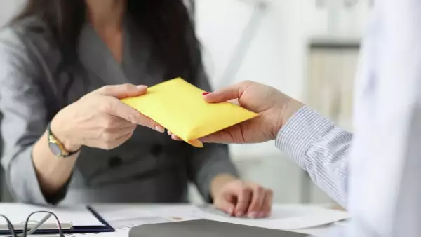Mujer recibiendo sobre de dinero. Si se trabaja el 20 de noviembre, así como se debe pagar por ser festivo.