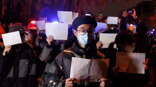 Personas guardan una vigilia con hojas de papel blancas en protestas por las restricciones para contener los contagios de covid-19 en Beijing, China.