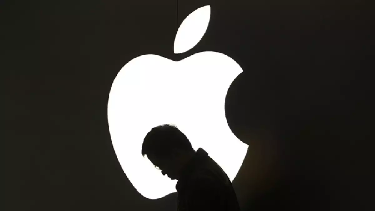 un hombre pasa frente al logotipo de apple